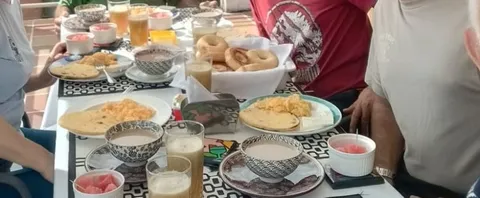 Desayuno tipo buffet servido: arepas, huevos pericos, buñuelos, chocolate y jugo